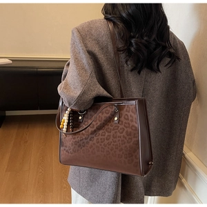 Detail of leopard print tote bag with beaded tassel charm on brown blazer outfit