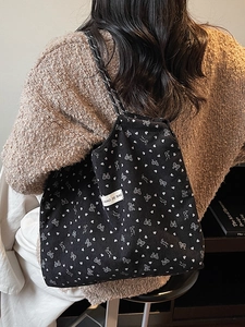 Black corduroy tote bag with heart patterns and rope shoulder straps shown on a model