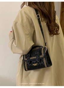 Detail of leopard print crossbody bag with gold studs and suede texture on beige coat