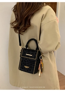 Detail of black leopard print crossbody bag with gold hardware and beaded charm detail