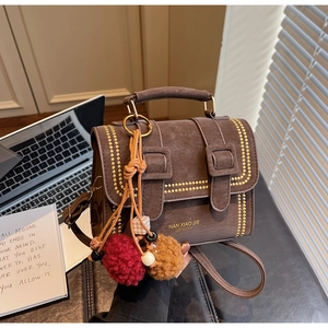 Nahaufnahme braune Vintage-Satteltasche mit Goldnieten und Plüsch-Anhänger Detail