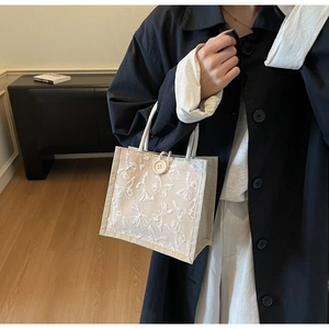 Detail of beige canvas tote with 3D butterfly embroidery and woven rope handles