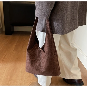Detail of leopard print tote bag featuring a gold button and soft suede-like texture
