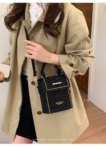 Detail of crossbody bag with leopard print, gold studs and metallic closure on trench coat