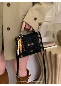 Detail of leopard print suede handbag with gold rivets and decorative wooden bead charm