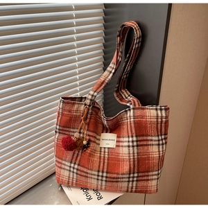 Close-up of red and white plaid tote bag with thick woven texture and fluffy pom-pom charm