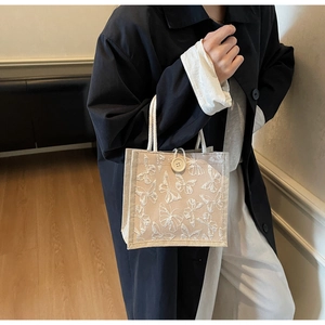 Detail of beige tote bag with white butterfly embroidery and cotton rope handle