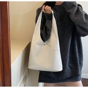 Detail of white woven tote bag with silver magnetic clasp shown on woman's shoulder