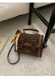 Detail view of leopard print handbag with wooden bead charm on a plush rug