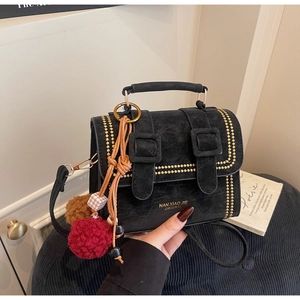 Detail der schwarzen Cambridgetasche mit goldenen Nieten und dekorativen Pompons