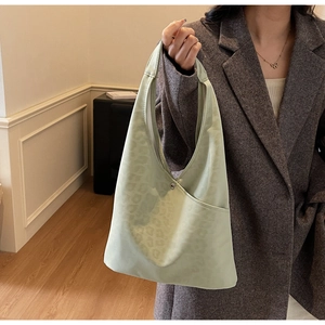 Detail of light green hobo bag with subtle leopard embossing and a metal snap closure