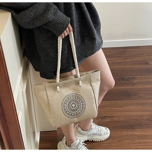 Detail of linen tote bag featuring a black mandala print and white woven rope handles