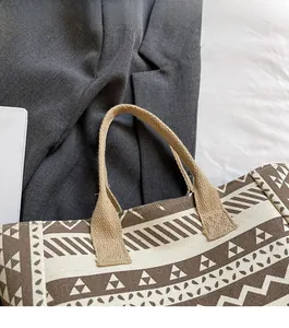 Detail of canvas tote bag featuring geometric ethnic patterns and braided thick handles