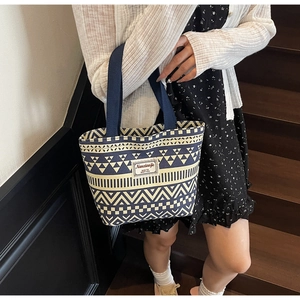 Detailed side view of a large canvas tote with geometric patterns and shoulder straps