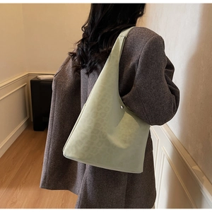 Close-up of light green matte tote bag featuring subtle leopard print and metal buckle