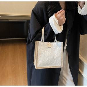 Detail of white butterfly embossed canvas bag with cotton rope handle and button closure