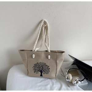 Detail of tree pattern on linen tote bag with white cotton rope handles and metal eyelets
