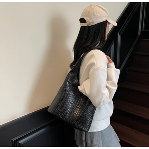 Detail of black hand-woven leather tote bag texture on a stylish minimalist model