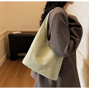 Detail of light green tote bag with subtle leopard texture and silver snap closure