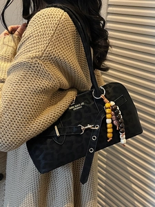 Minimalist black leopard print shoulder bag with bohemian wood beads on a beige sweater