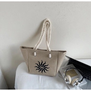 Close-up of beige linen tote bag with sun print and white cotton rope handles