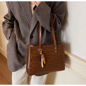 Macro shot of brown leopard print tote bag featuring colorful bead charms and shoulder straps