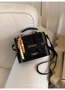 Macro detail of leopard print handbag with golden beads on suede fabric texture
