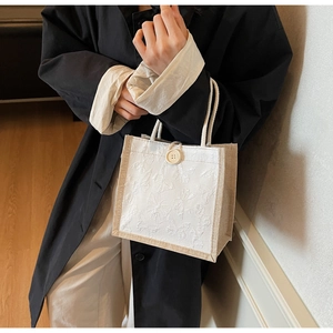Detail showing butterfly embroidery and rope handle on a stylish white tote bag