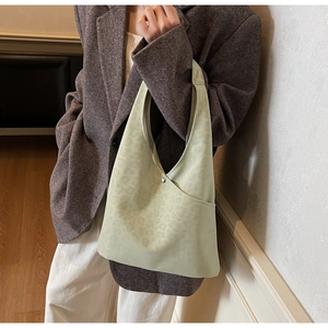 Close-up of light green suede tote bag featuring subtle leopard print and magnetic buckle