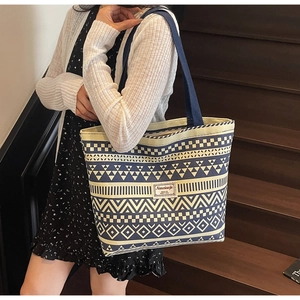 Detail of a geometric pattern canvas tote bag with Navy blue handles and logo patch