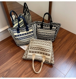 Artistic canvas tote bags with geometric prints displayed on a dark wooden floor