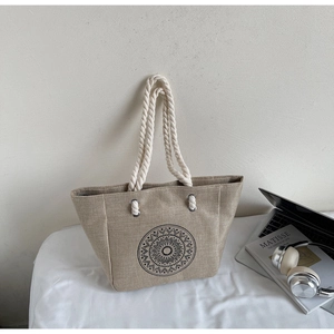 Detailed close-up of woven linen tote bag featuring a black mandala pattern and cotton rope straps