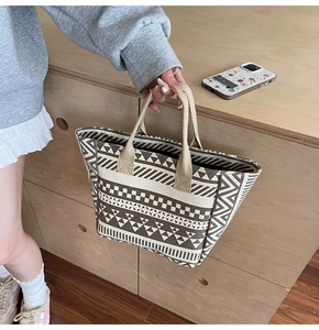 Detail of canvas tote bag featuring brown geometric patterns and woven handles
