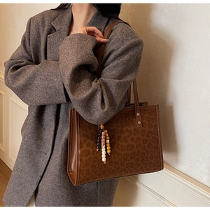 Brown leopard print tote bag with beaded pendant shown on woman in grey tweed blazer