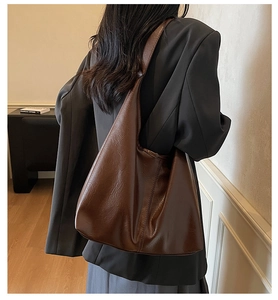Detailed back view of a dark brown vintage PU leather tote bag worn with a gray blazer