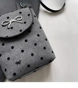 Detail of grey polka dot crossbody bag featuring silver bow buckle and wool texture