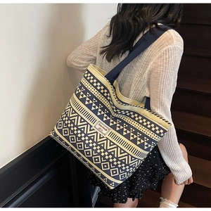 Detail of a geometric ethnic canvas tote bag with navy blue straps on a model