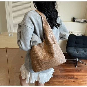 Detail view of brown woven leather tote bag with fine texture and silver metal buckle