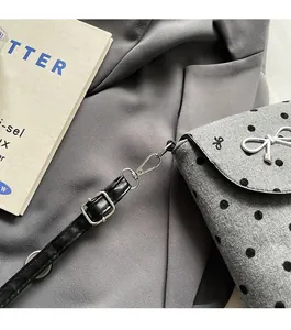 Close-up of silver bow buckle and hardware on gray polka dot felt crossbody bag