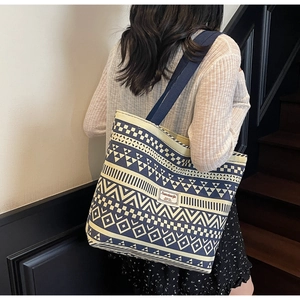 Detailed shoulder view of a blue and beige geometric canvas tote bag with woven handles