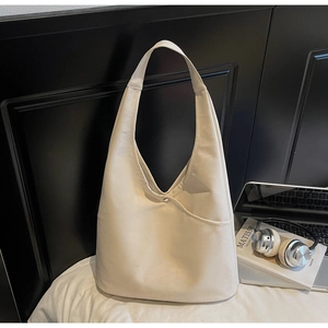 Detail view of large cream tote bag with front pocket in a professional office setting