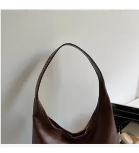 Close-up of wide curved top handle on a large dark brown tote bag for work and daily use