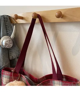 Detail of red checkered tote bag showing comfortable fabric strap and plush ball charm
