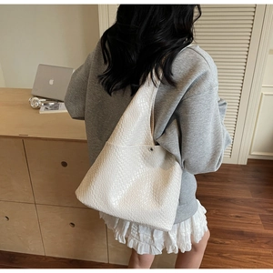Detail shot of white woven texture on a large tote bag worn on a woman's shoulder