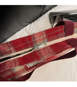 Close-up of the smooth silver zipper and red-white checkered fabric on the tote bag