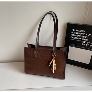 Detail of leopard print tote bag with brown faux leather and wooden bead tassel