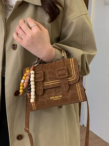 Vintage leopard print shoulder bag with gold rivets and beaded charm on beige coat