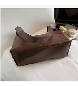 Detail of dark brown tote bag on a white cushion with lifestyle office accessories