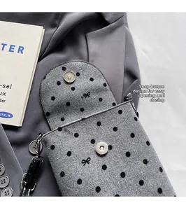 Detail of magnetic closure on grey polka dot felt crossbody bag with bow design