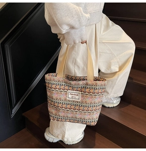 Ethnic pattern tote bag detail on a model standing on wooden stairs in natural light
